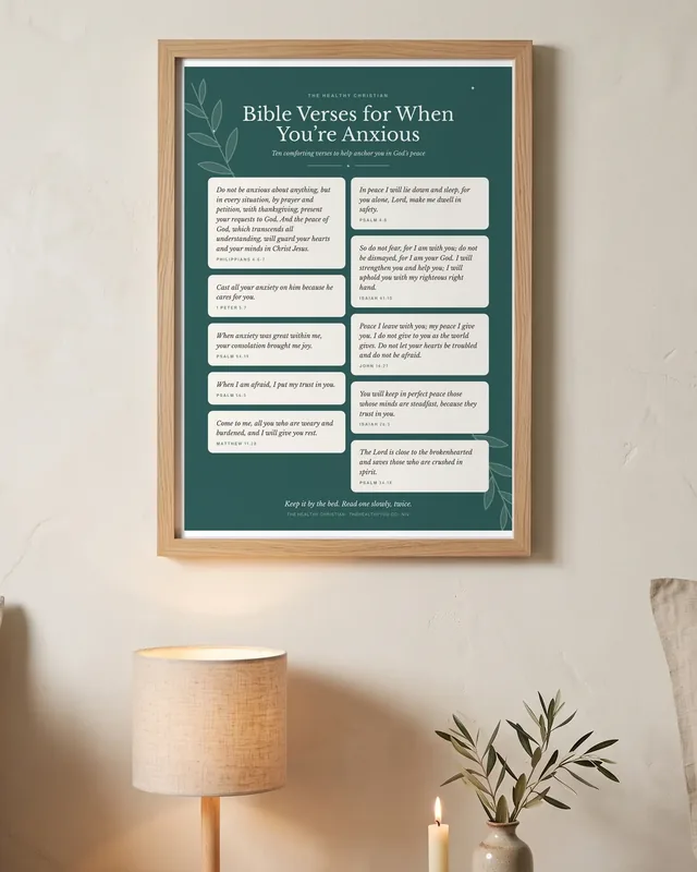 The Bible Verses for When You're Anxious poster in a light oak frame, above a bedside table with a lamp and a candle.